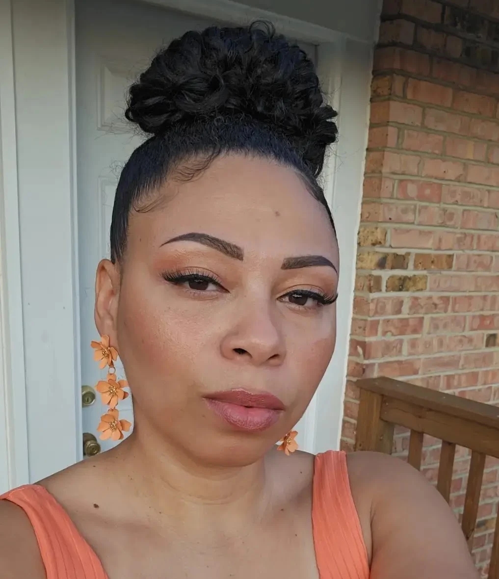 Close-up Selfie of Blog Author, Michaela. She is facing the viewer, her hair up in a bun, no smile on her face, only in her eyes.